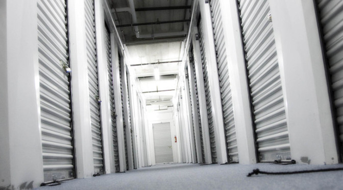 Well lit hallway of small storage units with white doors