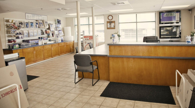 View of facility office overlooking the front desk area with moving and packing supplies hanging from wall and on counter area