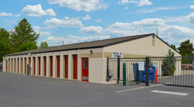 Outdoor area of small storage units with red doors with a gated entrance
