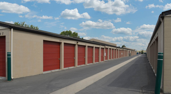 A row of outdoor storage units with red doors in a clean environment