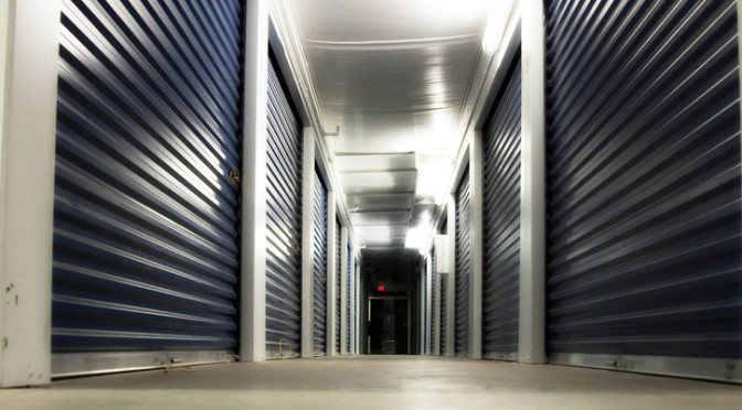 Well lit hallway of indoor storage units with blue doors