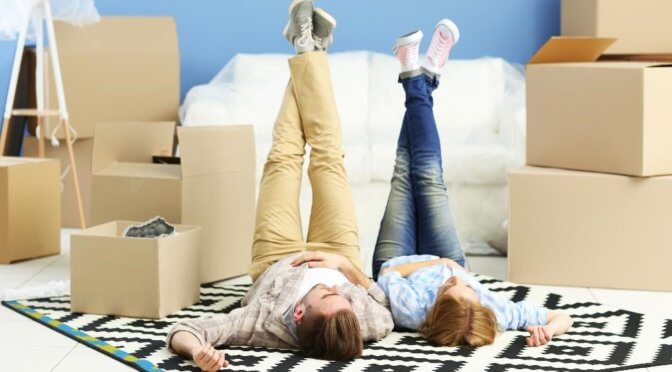 a couple lying side by side on a rug with moving boxes around them