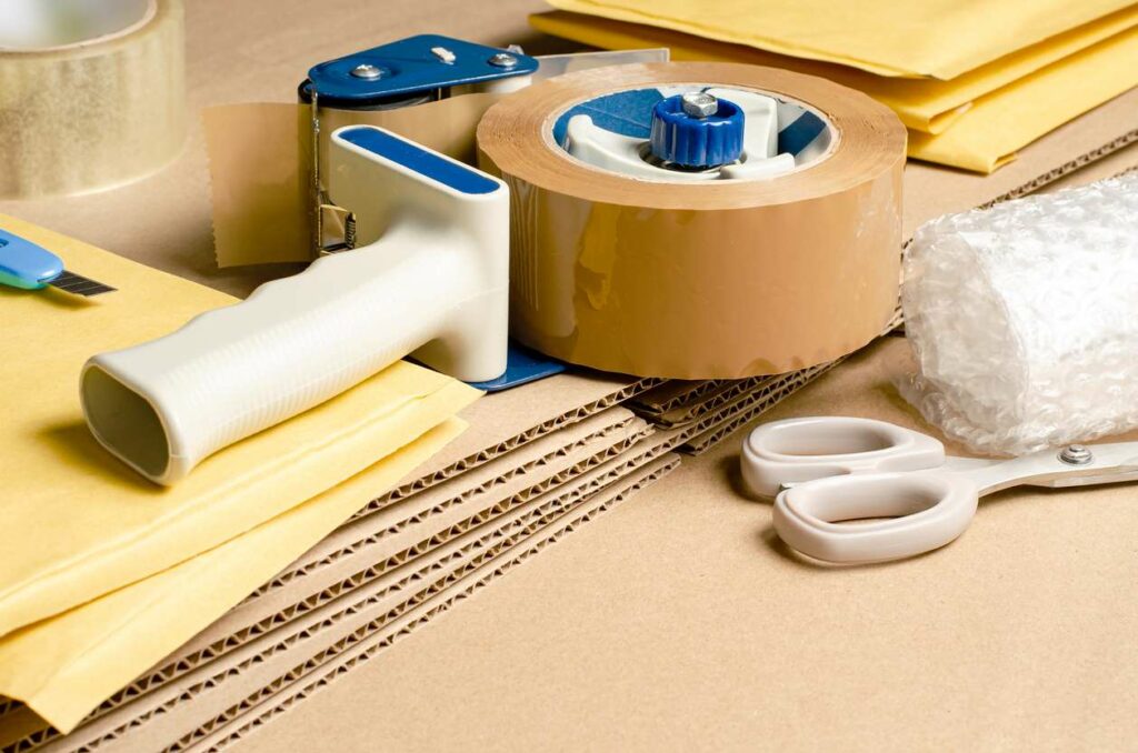 An assortment of cardboard, tools, and envelopes for packaging goods in an online store.
