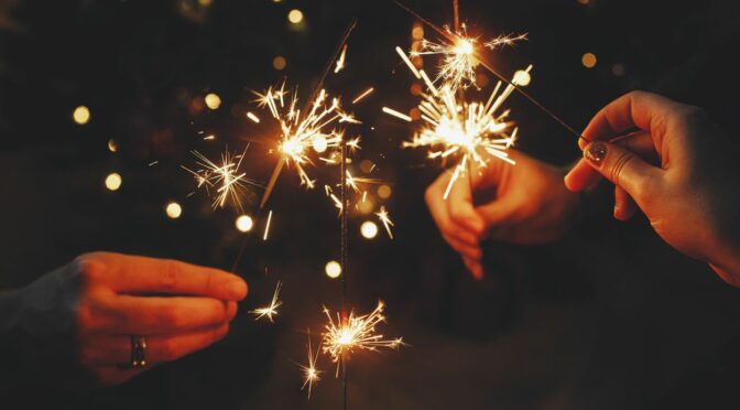 Hands holding sparklers to celebrate the new year.
