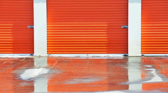 Snowy orange self storage unit door at a storage facility.