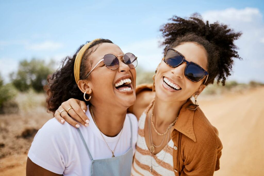 Two women smiling in embrace as they laugh in the desert