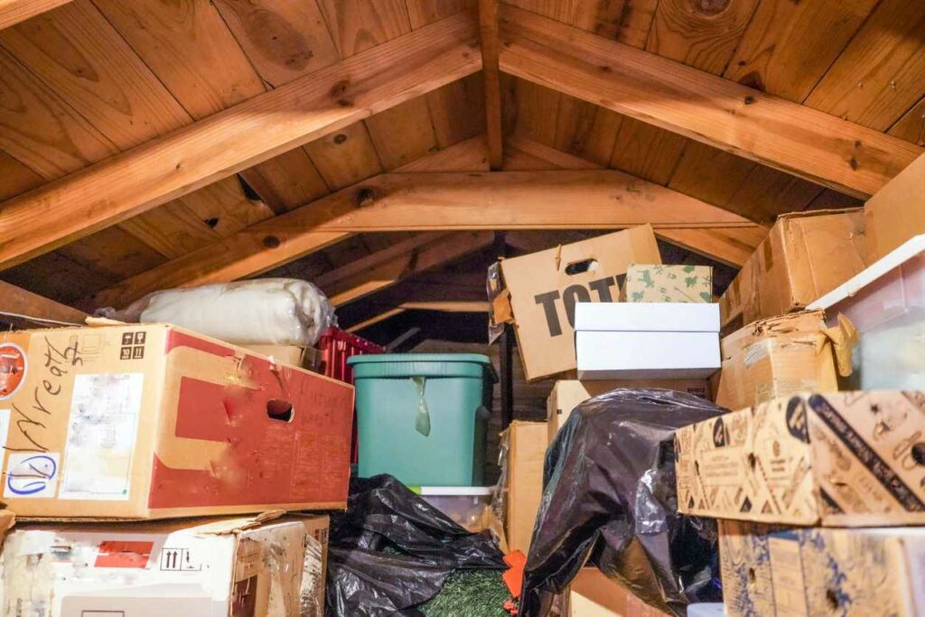 Attic space cluttered by boxes and bins in storage
