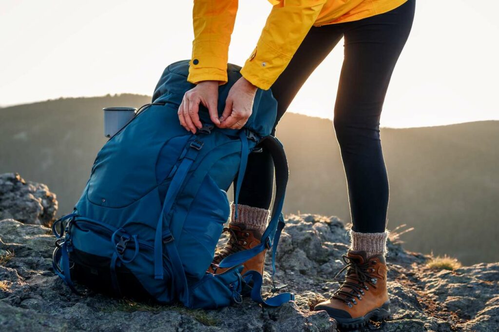 A woman opening a backpack while they hike down a trail