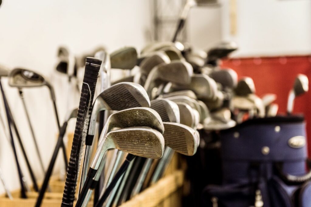 Pile of golf clubs inside a storage room.