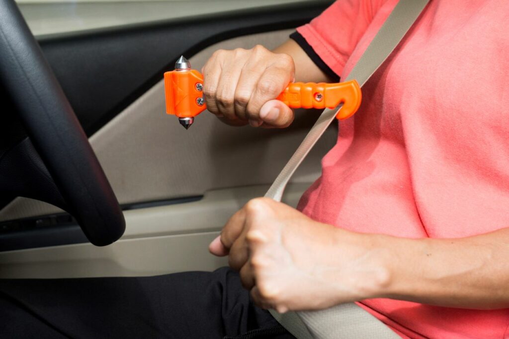 A seatbelt cutter is being used to cut through a safety restraint in a car.