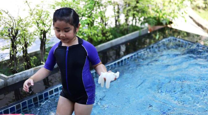 A young girl is playing in the swimming pool