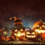 Several jack-o’-lantern pumpkins are sitting on a wooden table.