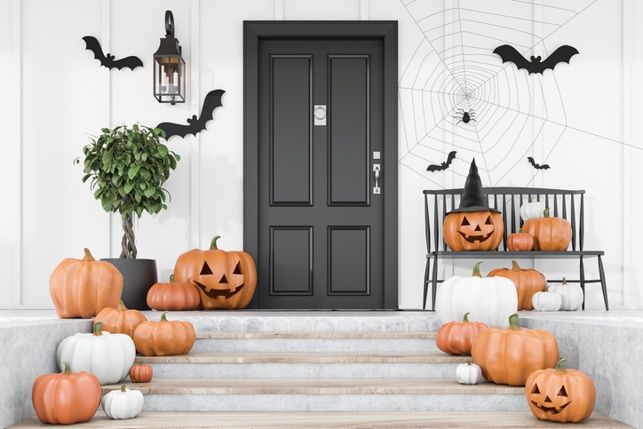 Carved pumpkins on the stairs of a white house with a black door. 